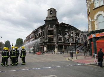 Firefighters douse the end of a fire that destroyed a department store in Tottenham